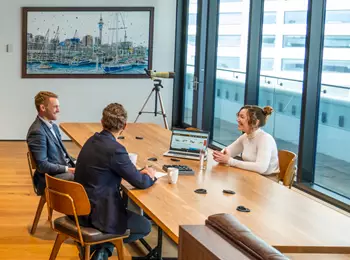 Clients working in a modern coworking shared space on a long table with great booths in Servcorp 139 Quay Street, Auckland